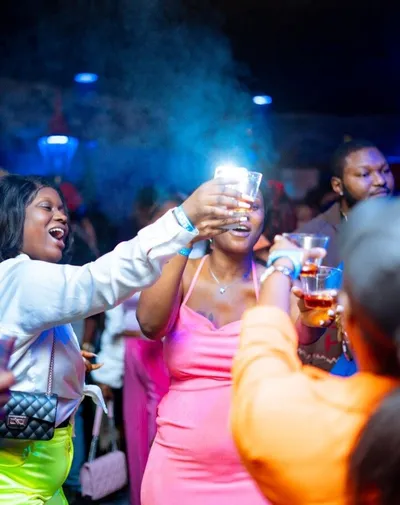 Two women raising glasses in a toast at a lively nightclub event
