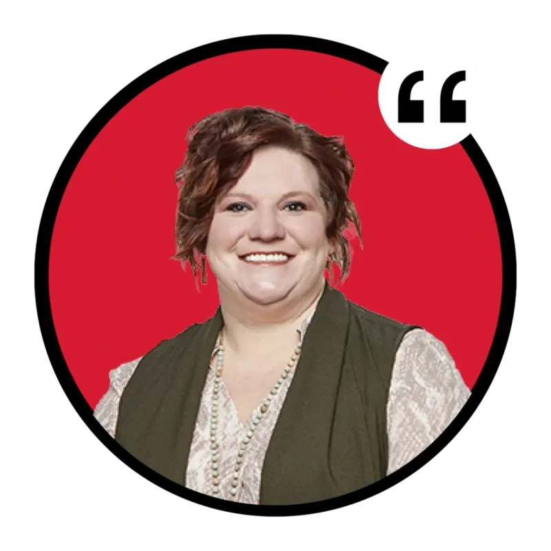 Smiling woman with short auburn hair wearing a green vest and beaded necklace against a red circle background