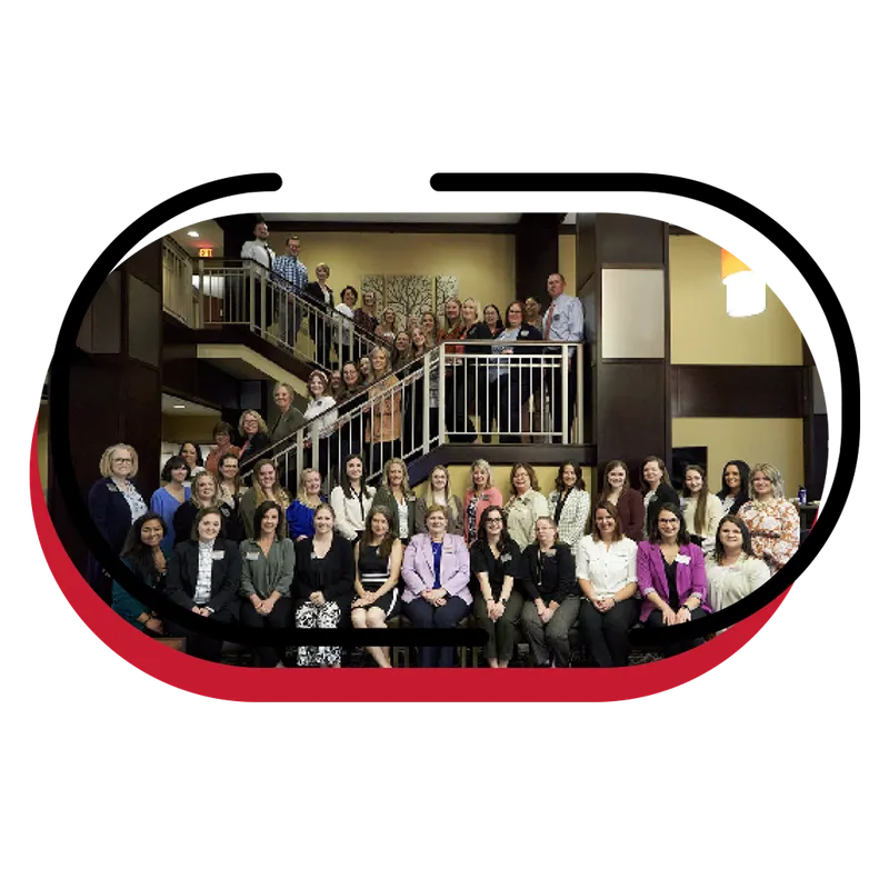 Large group of professionally dressed people posed on a staircase inside a building