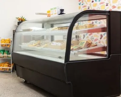 Curved glass deli display case stocked with packaged foods on multiple shelves