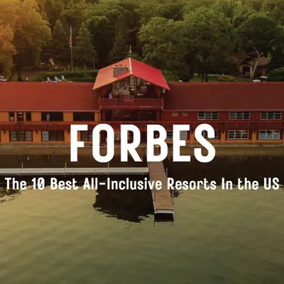Lakeside resort with red roof and dock, surrounded by trees, with Forbes overlay text