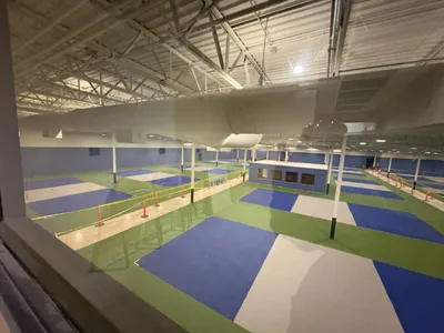 Aerial view of a large indoor facility with blue and green pickleball courts