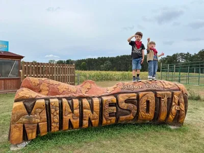 Two children standing atop a large carved wooden Minnesota sign at Walgoch Farms