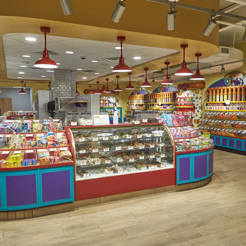 Colorful candy shop interior with glass display cases, bulk sweets, and red pendant lights