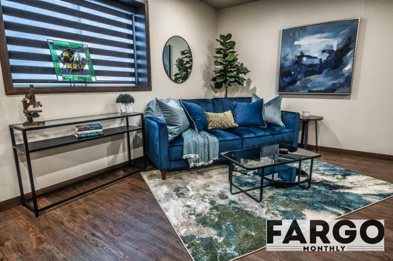 Blue velvet sofa with throw pillows on an abstract rug in a styled living room