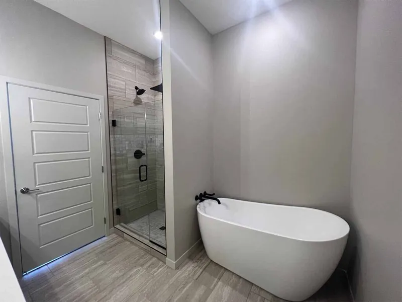 Modern bathroom with freestanding white soaking tub and glass-enclosed tile shower