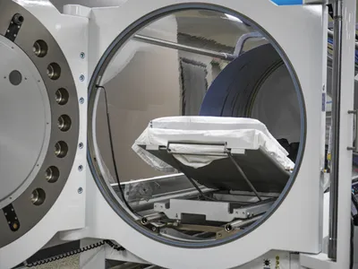 Open circular hatch of a hyperbaric oxygen chamber with a padded interior bed
