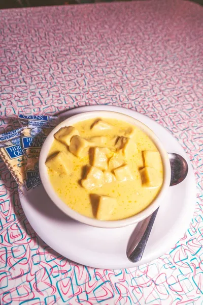 Bowl of creamy knoephla soup with dough dumplings on a patterned tablecloth