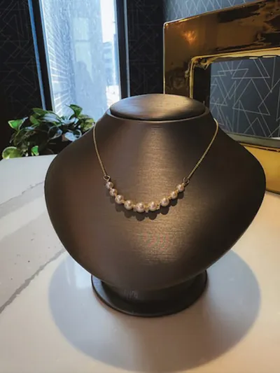 Pearl strand necklace on a dark jewelry bust display