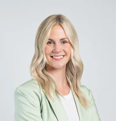 Smiling woman with wavy blonde hair wearing a light green blazer