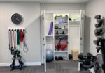 Organized garage gym with wall-mounted equipment, metal shelving, and weight rack