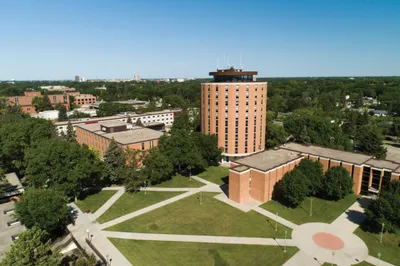 Aerial view of a brick university campus with a tall tower building surrounded by green trees