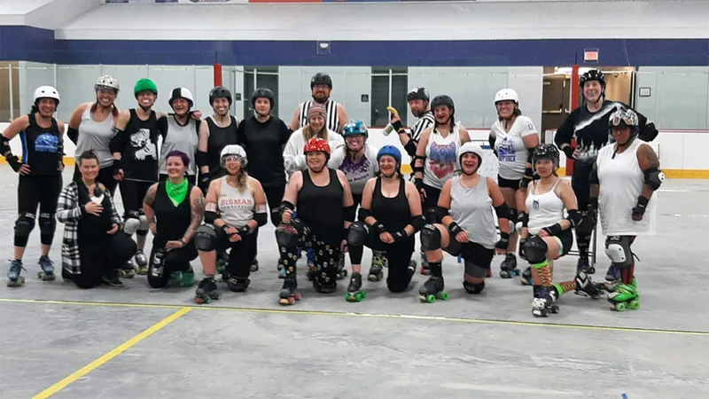 Large group of roller derby players in helmets and gear posing on a rink floor