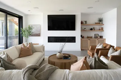 Bright living room with linen sofas, round wood coffee table, linear fireplace, and wall-mounted TV
