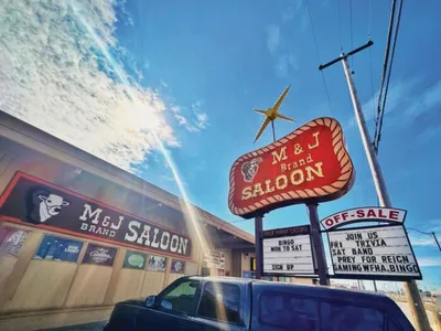 M&J Brand Saloon exterior with vintage marquee sign and gold star under a blue sky