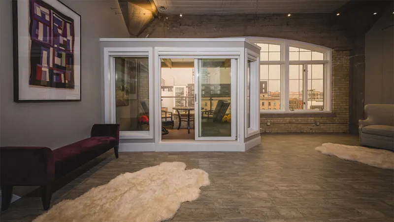 Loft interior with white bay windows, exposed brick, sheepskin rugs, and a velvet bench
