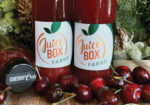 Two bottles of Juice Box Fargo cherry juice surrounded by fresh cherries
