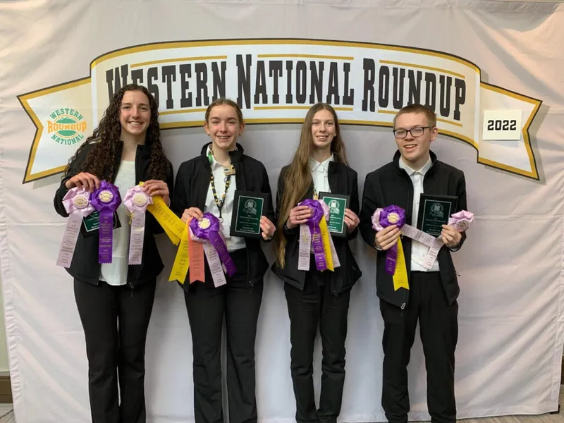 Four teens holding plaques and ribbons in front of a 2022 Western National Roundup banner