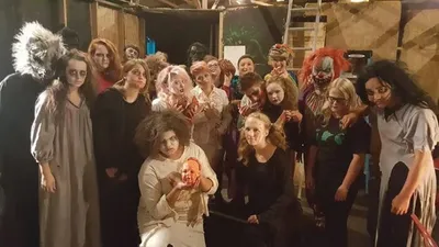 Large group in Halloween costumes and horror makeup posing indoors