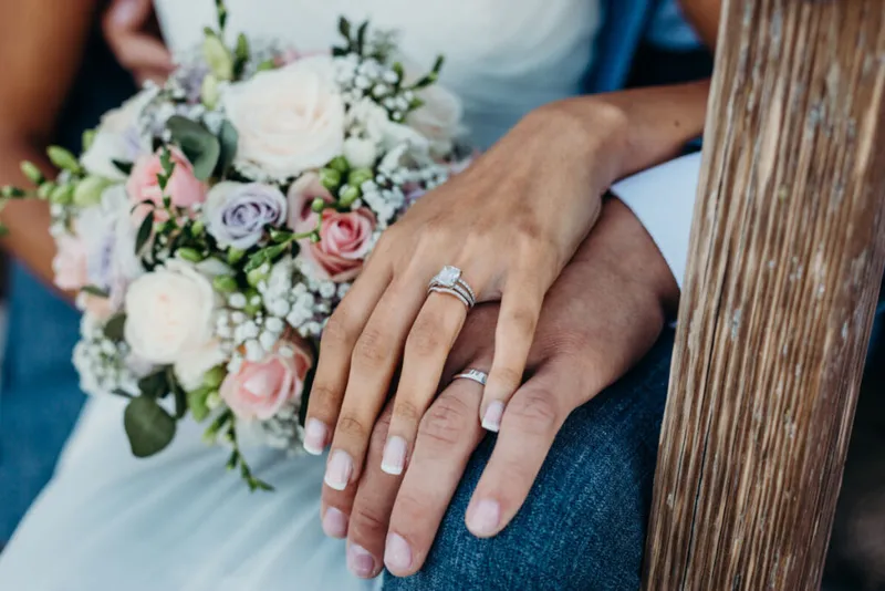 married couple holding hands showing their wedding rings close up