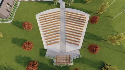 Aerial rendering of an open-air amphitheater with rows of wooden seating surrounded by green lawn and autumn trees