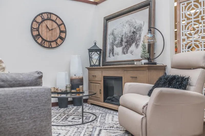 Cozy living room vignette with cream leather recliner, wood fireplace console, bison artwork, and large rustic wall clock