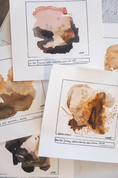 Several small watercolor studies in earthy brown and blush tones spread on a white surface