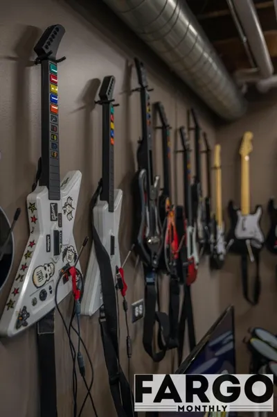 Row of Guitar Hero controllers mounted on a wall, white stickered one in foreground