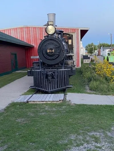 Vintage black steam locomotive on display beside a red depot building