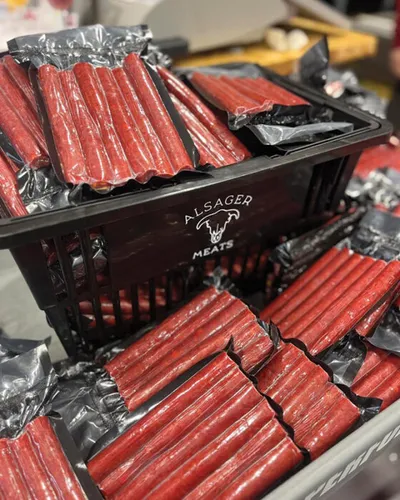 Stacks of red meat snack sticks in black trays labeled Alsager Meats