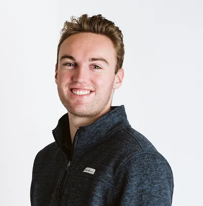 Smiling young man with short brown hair wearing a dark zip-up fleece