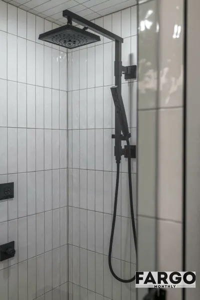 Matte black dual rain shower head and handheld wand on white vertical tile