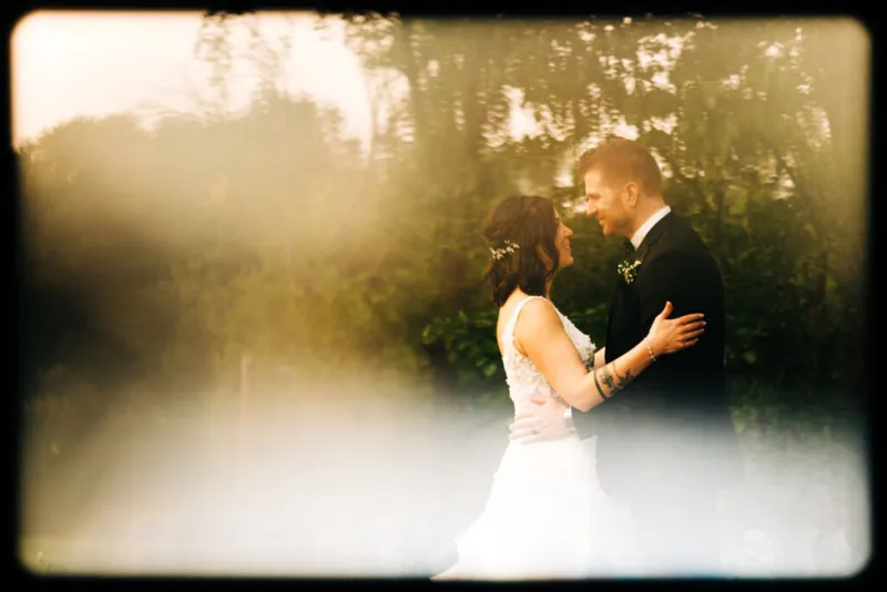 Bride and groom embracing outdoors in warm golden light among lush trees