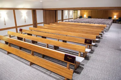 Rows of wooden pews in a softly lit funeral home chapel