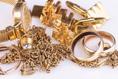 Assorted gold jewelry including rings, chains, cufflinks, and a watch piled together