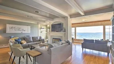 Bright living room with gray sofas, fireplace, and large windows overlooking a lake