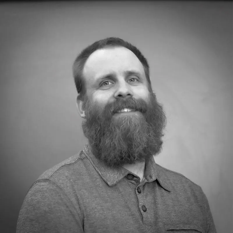 Smiling bearded man in a polo shirt, black-and-white portrait