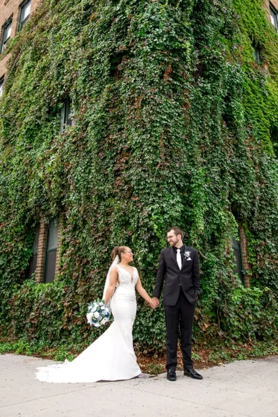 Bride and groom holding hands in front of an ivy-covered brick building