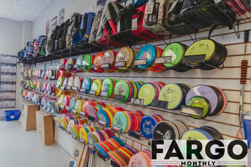 Wall display of colorful disc golf frisbees and backpacks inside a retail store