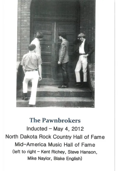 Four young men standing near a building entrance in a vintage black-and-white photo