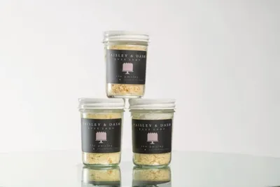 Three small glass jars with dark labels stacked in a pyramid on a reflective surface