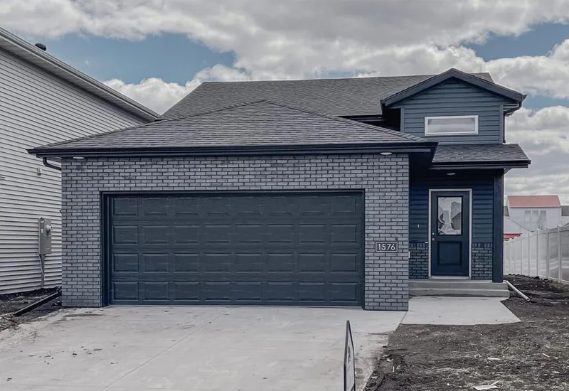 New two-story home with gray brick facade, dark blue siding, and double garage