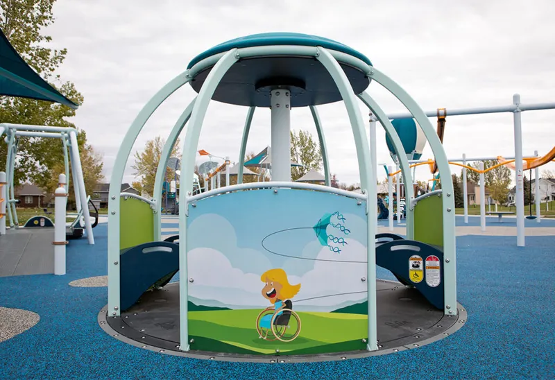 Accessible merry-go-round with wheelchair-user cartoon graphic at a colorful inclusive playground