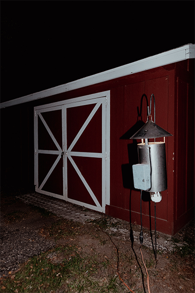 Red barn with white X-patterned doors and a metal bug zapper at night