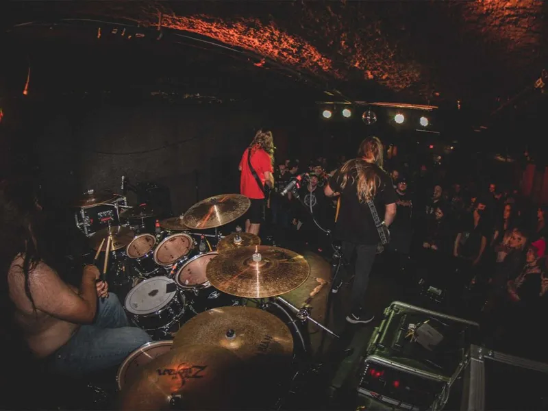 Heavy metal band performs on a dimly lit stage before a packed crowd