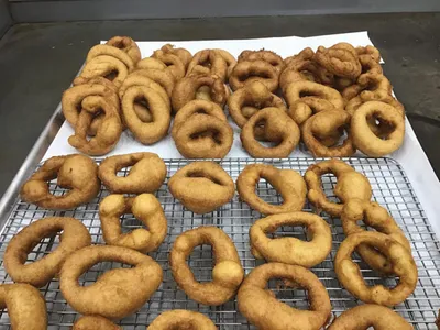 Golden fried onion rings arranged on a wire cooling rack and paper-lined tray