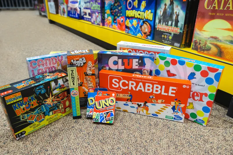 Assortment of board games including Scrabble, Clue, Uno, Twister, and Candy Land displayed on a store floor