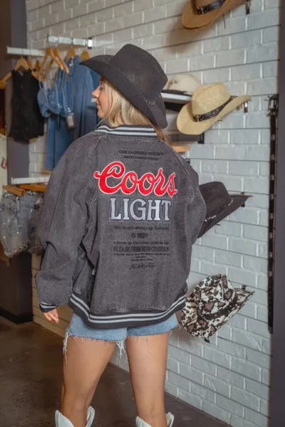 Woman in black cowboy hat and Coors Light graphic jacket poses in a boutique