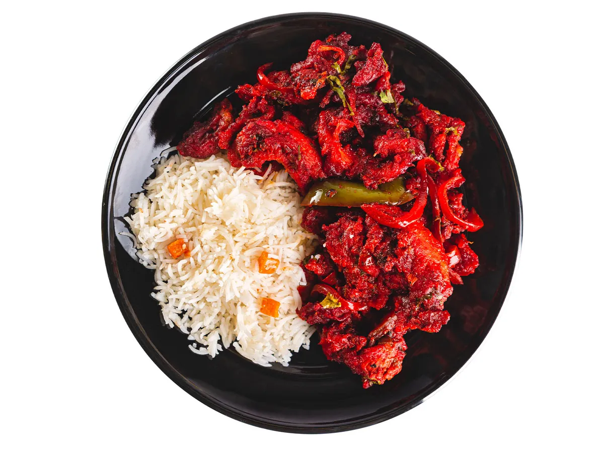 Black plate with white rice and deep-red spiced meat stir-fried with peppers