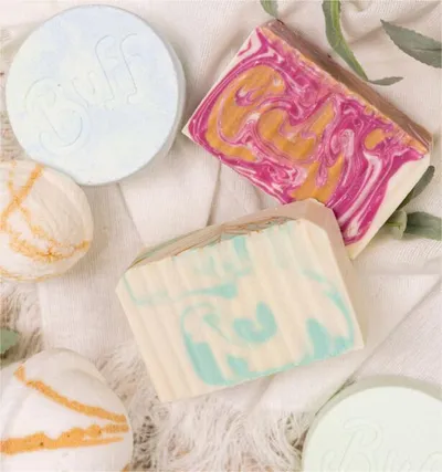 Assorted handcrafted soap bars and bath bombs with colorful swirled patterns on a soft cloth